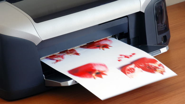 Desktop printer producing red hue photos on glossy paper.