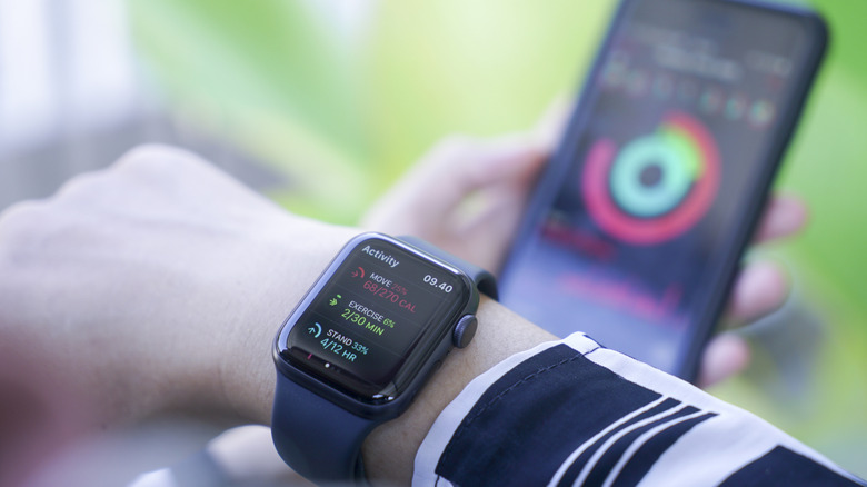A person using the Apple Watch with an iPhone (seen in the background.