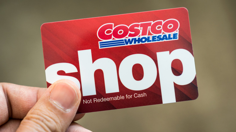 A closeup of a hand holding a red Costco Shop Card