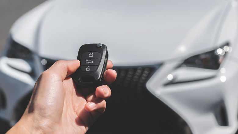 A person using a key fob to unlock a nearby car