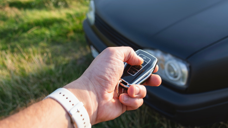 A person wearing a watch holding a key fob