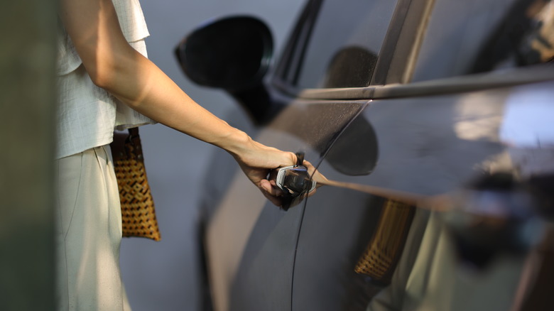A woman opening a car door.