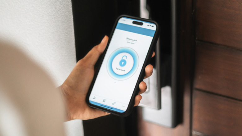 A person using an app on an iPhone to unlock a smart lock.