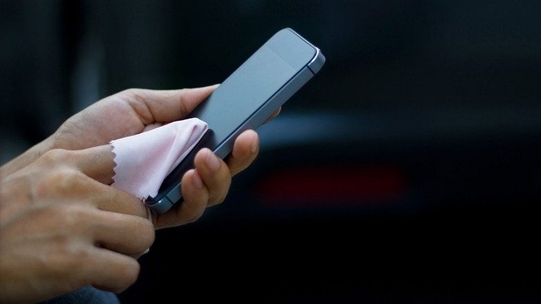 Close-up of hands cleaning phone with microfiber cloth