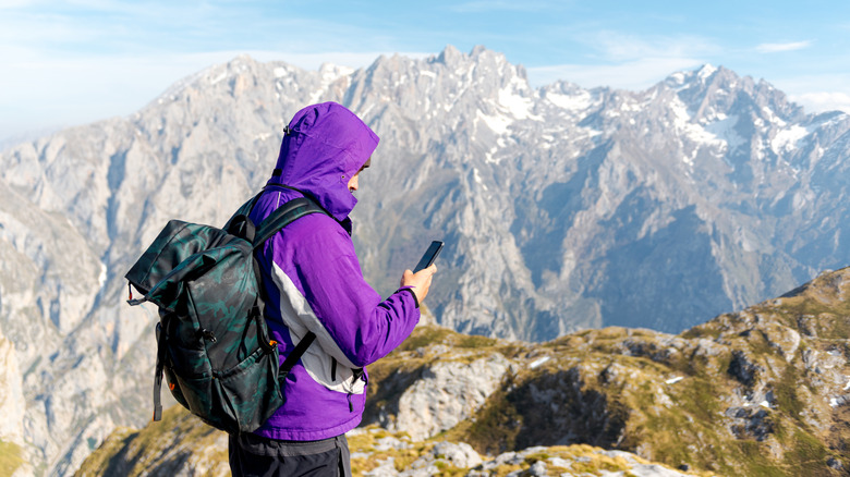 Hiker using phone in remote location up in the mountains.