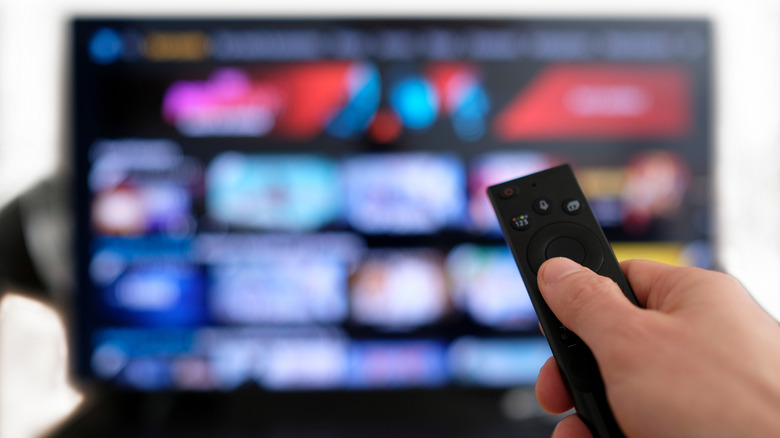 a hand holding a remote up toward a TV