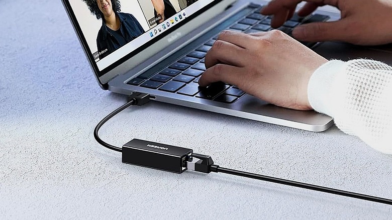 Ugreen USB to Ethernet adapter plugged into laptop for internet.