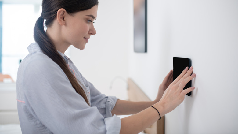 Woman installing a tablet on a wall