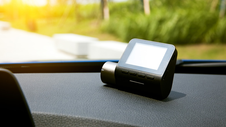 Close-up of a dash cam resting on the front dash of a vehicle