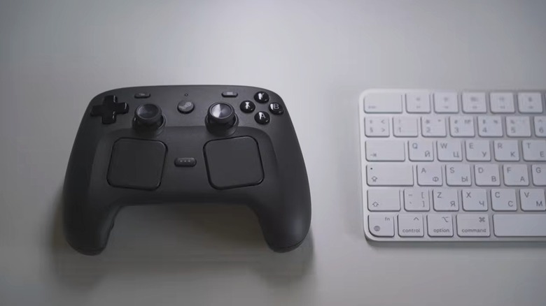 A Steam Controller next to an Apple keyboard on flat white table
