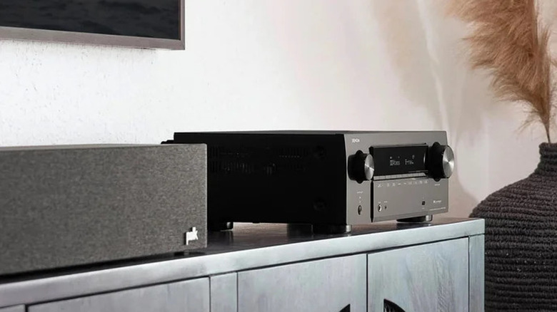An AV receiver and center speaker set up on a TV stand.