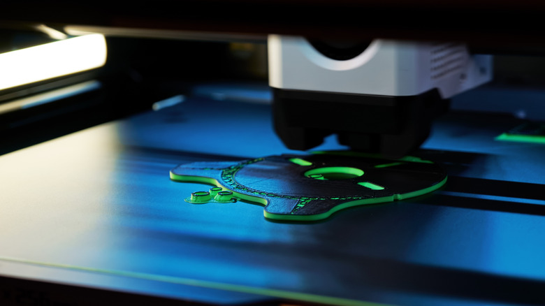 A 3D printer layering green filament.