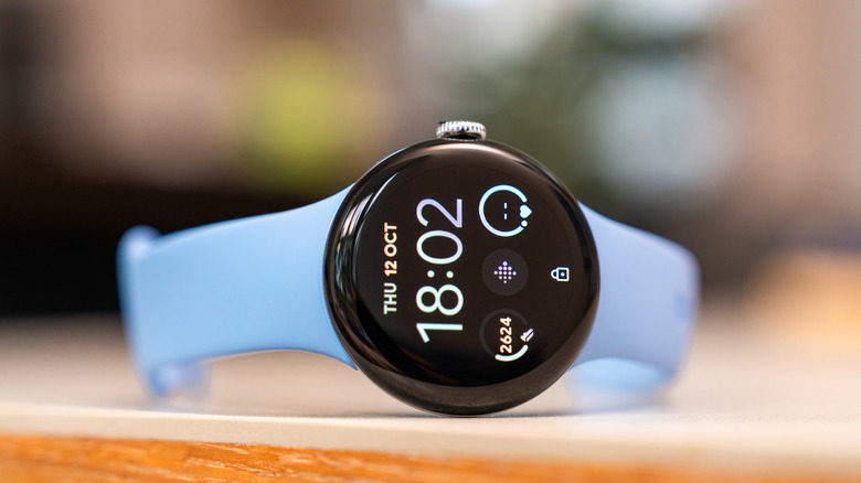 A Google Pixel Watch 2 with a light blue band sits sideways on a countertop