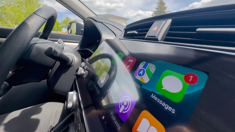 Interior of a car with Apple CarPlay screen showing app icons
