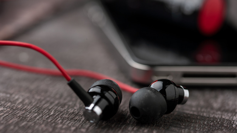 Wired earbuds with phone in the background and blurred