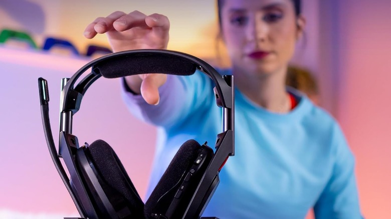 Woman in background reaching for black Logitech G Astro A50 gaming headset