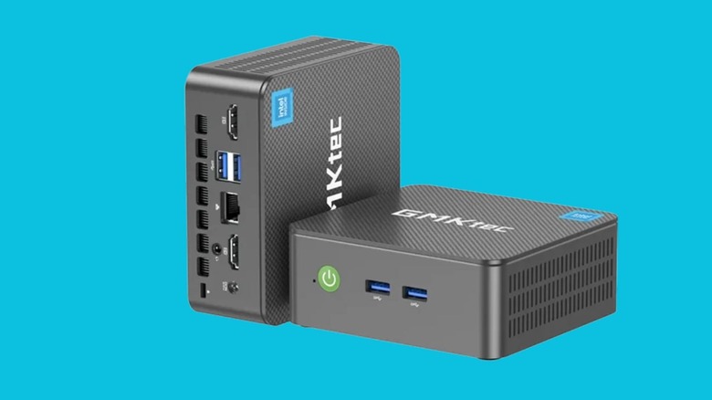 Two black GMKtec mini PCs showing USB and HDMI ports against a blue background.