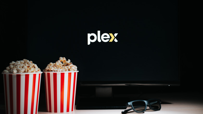 The Plex logo displayed on a TV screen with two popcorn buckets and 3D glasses in front.