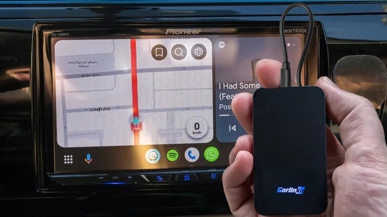 Person holding Carlinkit 2air in front of Pioneer aftermarket head unit displaying Android Auto interface