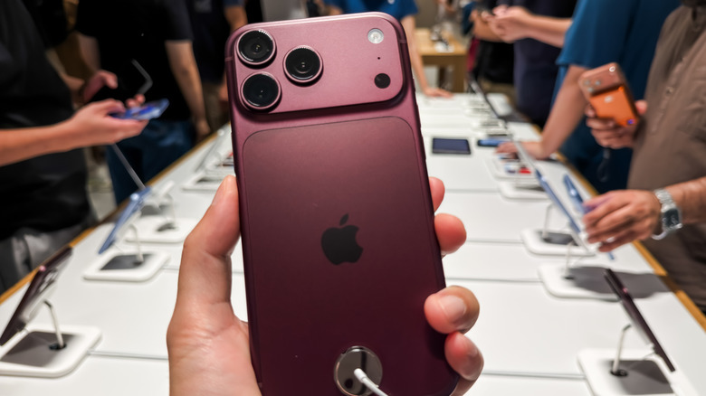 Person holding an iPhone 18 Pro in a phone store.