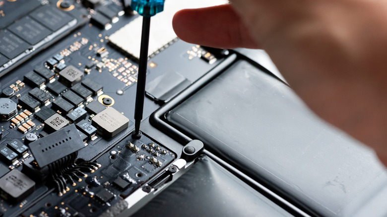 Technician unscrewing components to repair a laptop