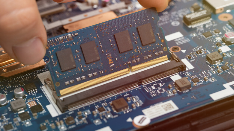 RAM stick being plugged into a PC motherboard