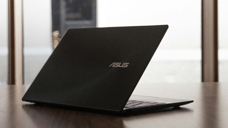ASUS laptop on a modern table in a brightly lit room.