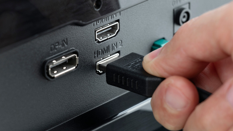 An individual inserting an HDMI cable into a port