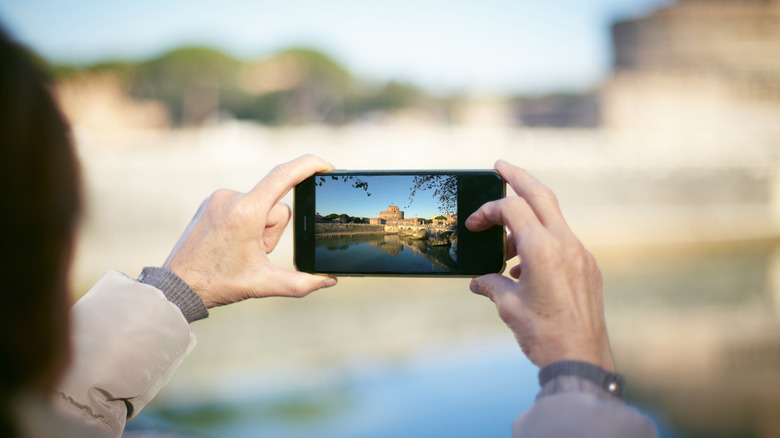Person capturing a picture of Castel Sant Angelo in Rome on a smartphone