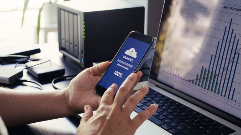 Someone uploading files to the cloud with notification on phone screen