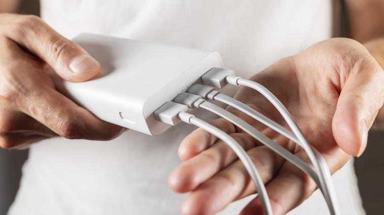 A person holding a power bank with multiple cables plugged into it