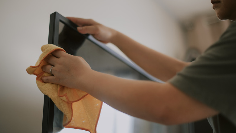 A person cleaning a TV screen.