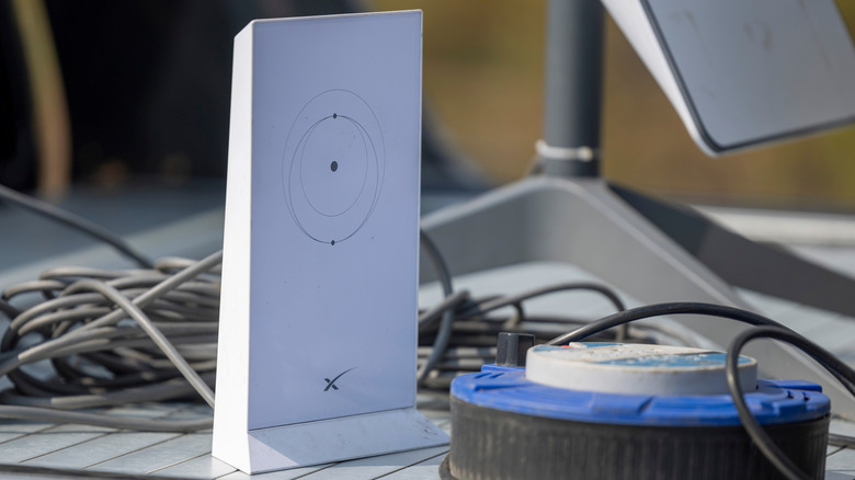A Starlink router standing upright next to antenna