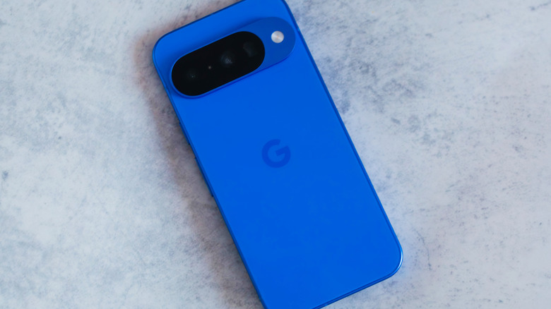 The Google Pixel 10 smartphone in blue on a gray marble-like background.