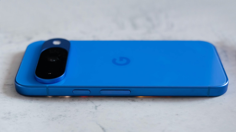A Google Pixel 10 phone sideways in blue on a gray marble-like surface.