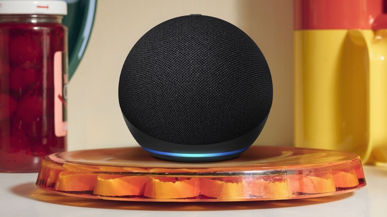 Black Alexa Echo Dot surrounded in kitchen surrounded by cups and jars.