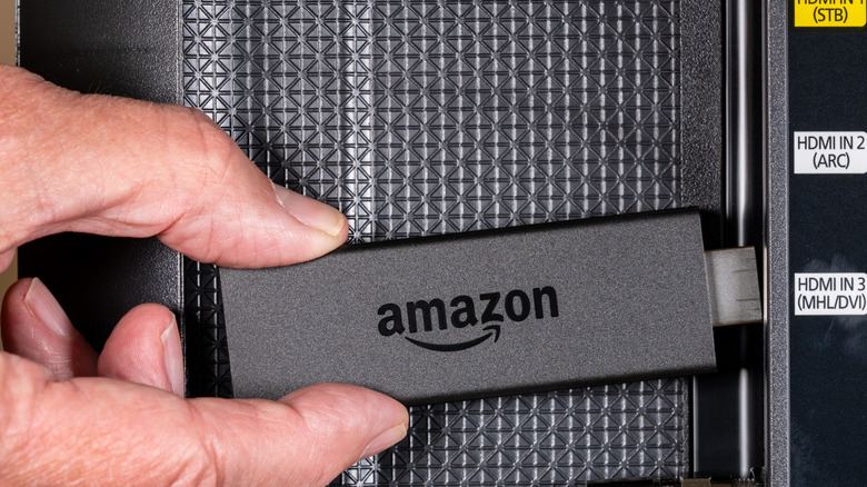A person connecting an Amazon Fire TV Stick to a TV.
