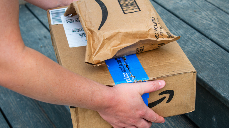 Amazon Prime packaged delivery boxes a person is picking up from a porch