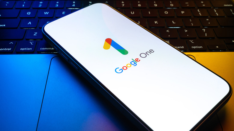 Google One logo on phone resting atop a keyboard.