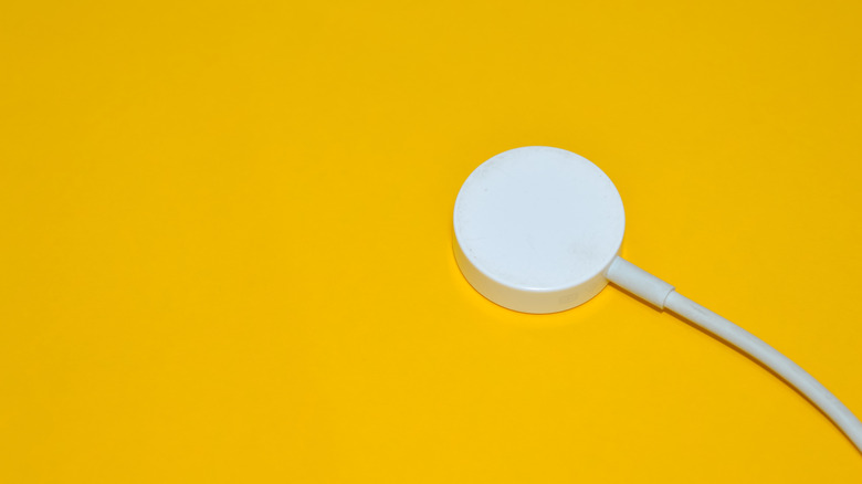 An Apple Watch charger against a yellow backdrop