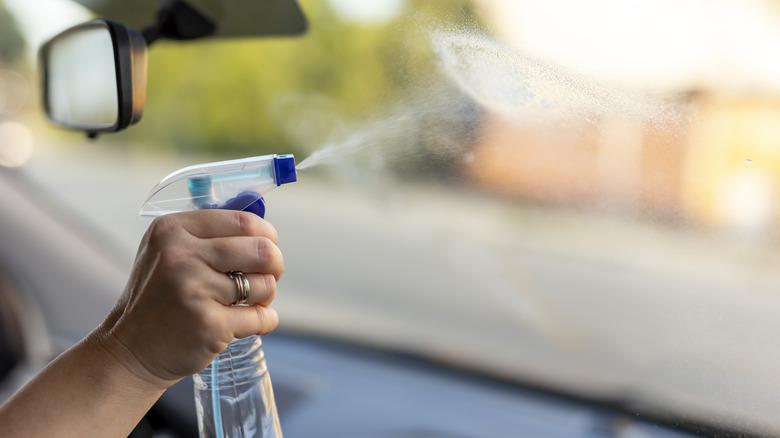 Spraying cleaning fluid on a car windshield