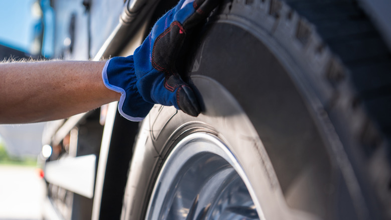 Closeup of someone inspected a truck tire's conditions.