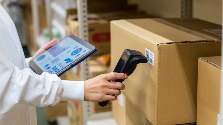Person using an RFID scanner on a barcode in a nondescript warehouse.