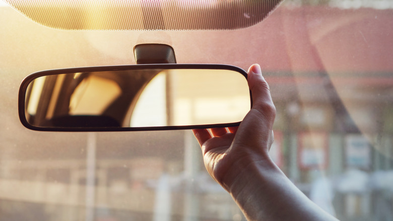 a hand adjusting a car rear view mirror