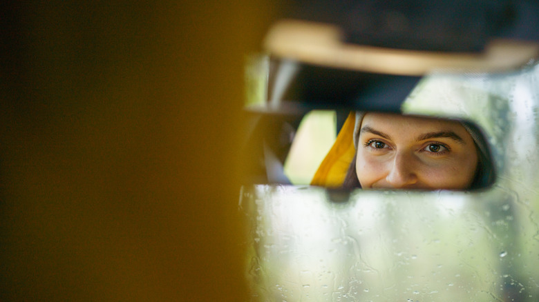 a woman smiling in a car rear view mirror