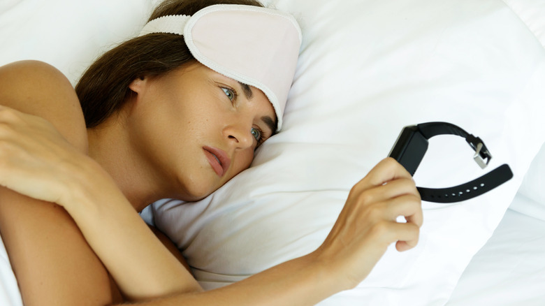 Sleeping woman looking at smartwatch
