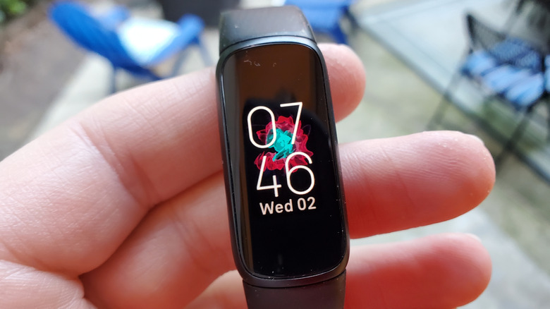 A fitness tracker showing the date and time on the screen