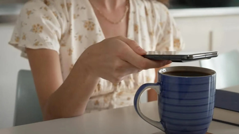 Woman taking temperature reading of coffee in a mug with a Google Pixel Pro