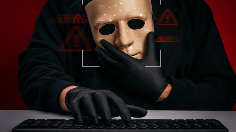 Ominous gloved hands at a keyboard holding a digitized mask surrounded by warning symbols