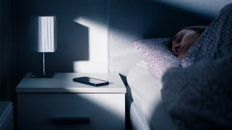 A person sleeping next to their smartphone laying on a table